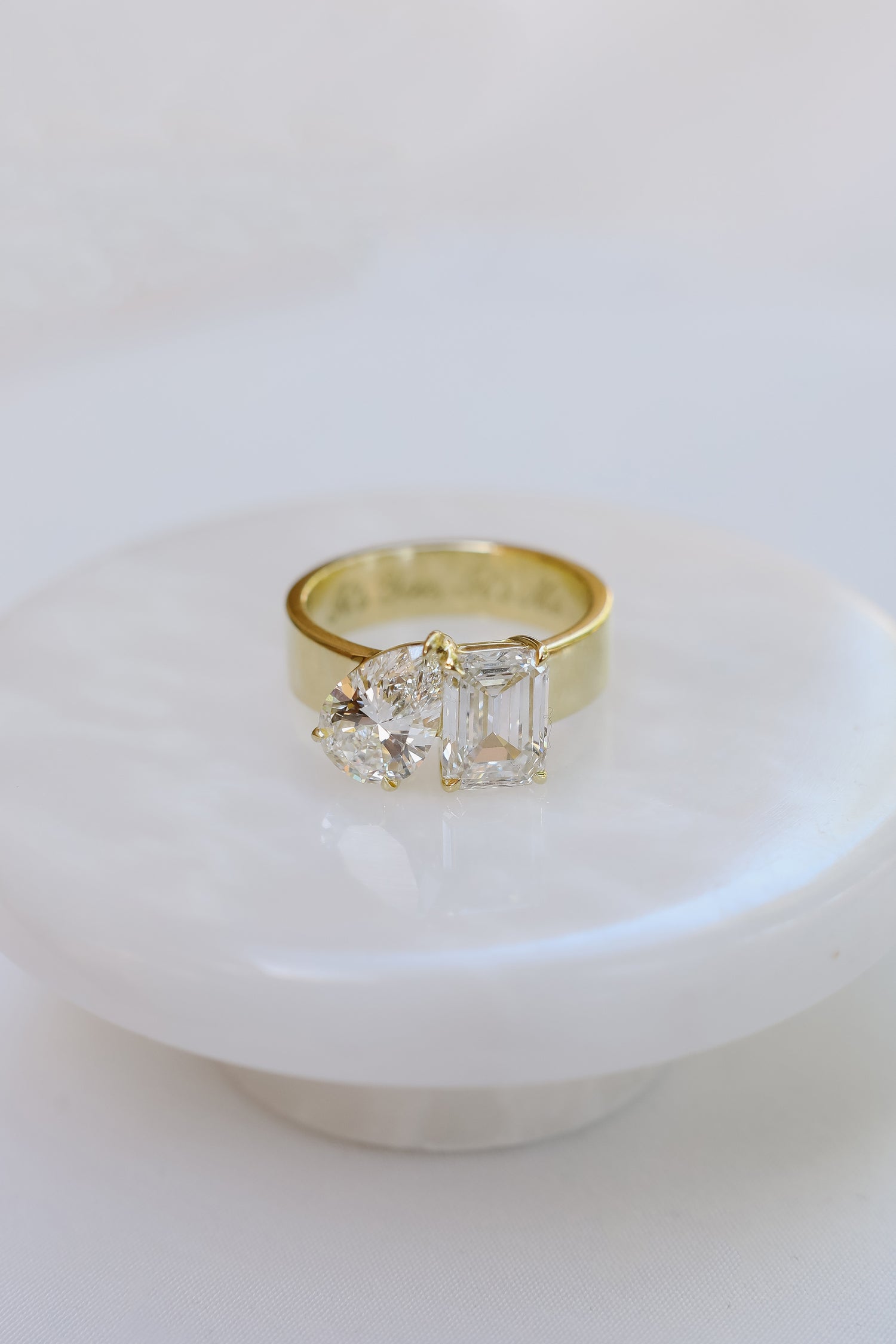 18k yellow gold Toi Et Moi Ring featuring a 2 ct Emerald and 1.5ct Pear with a 5.5mm cigar band. Engraved with it's you, it's me.